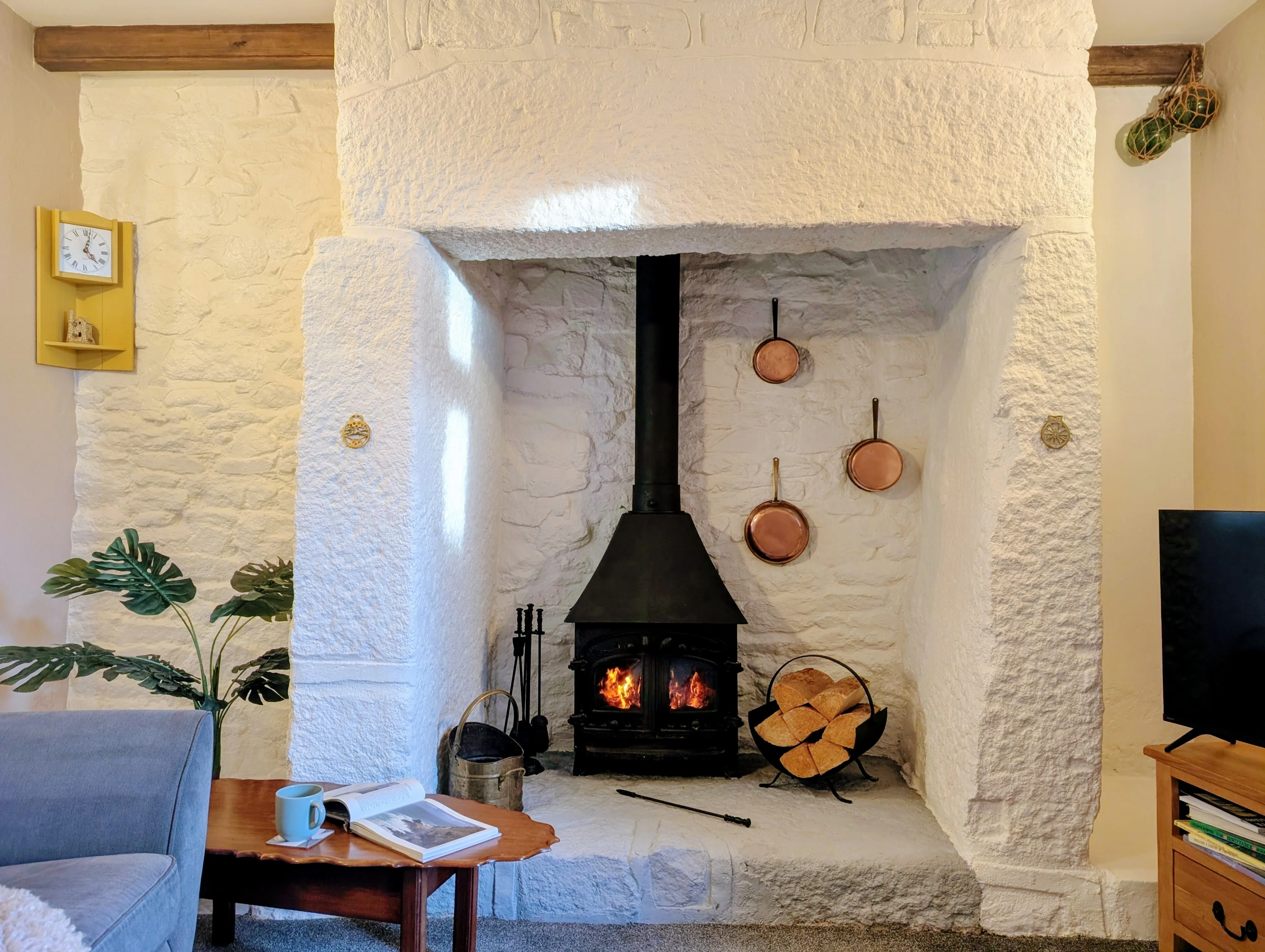 Little Avalon's wood burner in the original granite fireplace, copper pans hanging.