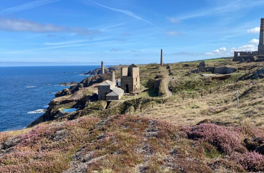A view of Geevor Tin Mine, featuring its historic buildings and winding gear, set against the rugged Cornish landscape.
