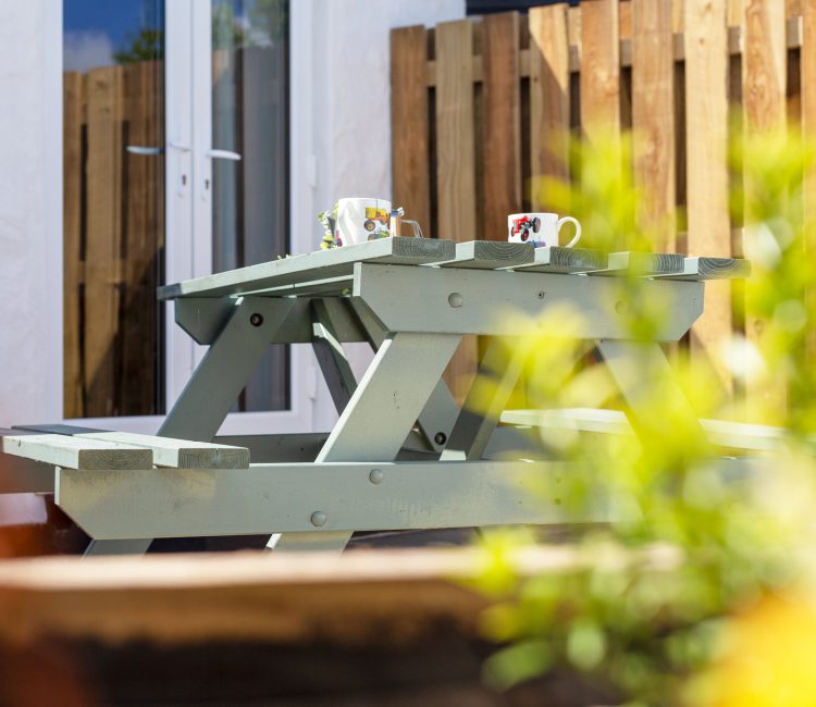 Spacious patio with a green picnic table and rustic planters at The Tractor Shed.